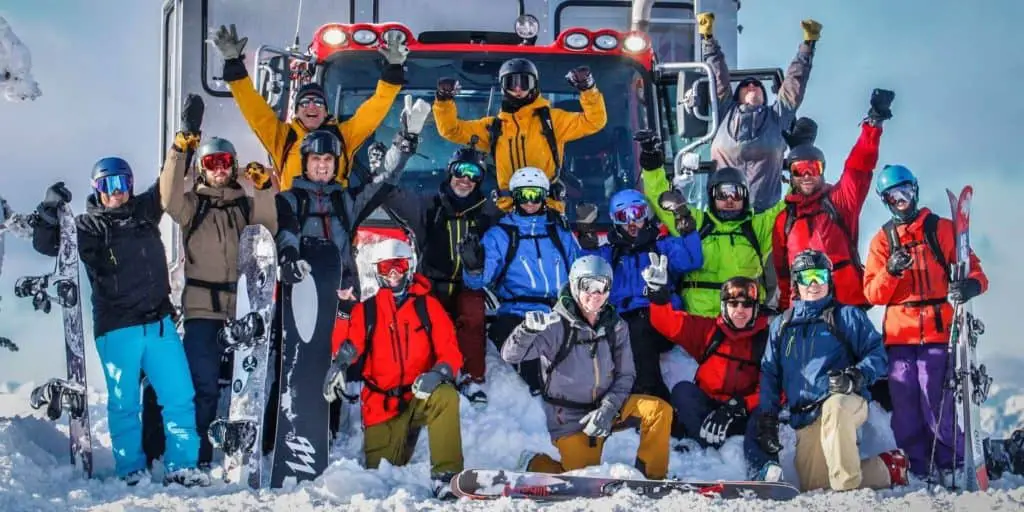 A group of skiers standing in front of a snowcat at Baldface Cat Skiing Lodge.