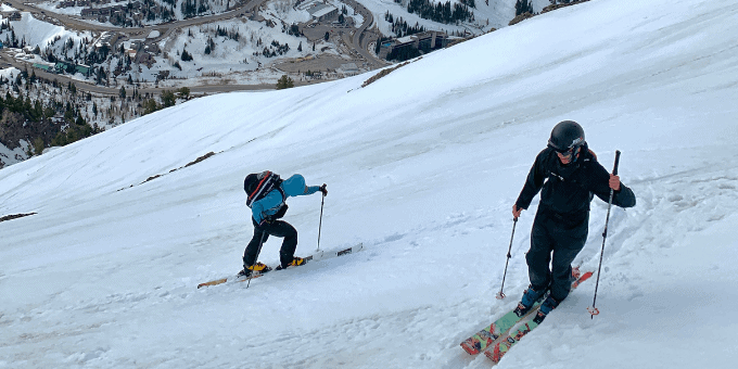 Skiers walking uphill with backpacks
